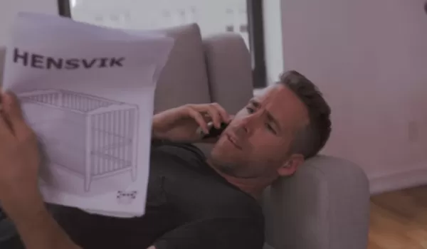 Ryan Reynolds ligger på soffan och läser en instruktion från IKEA