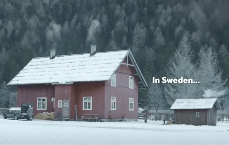 Rödmålad stuga i vinterlandskap med texten "In Sweden"