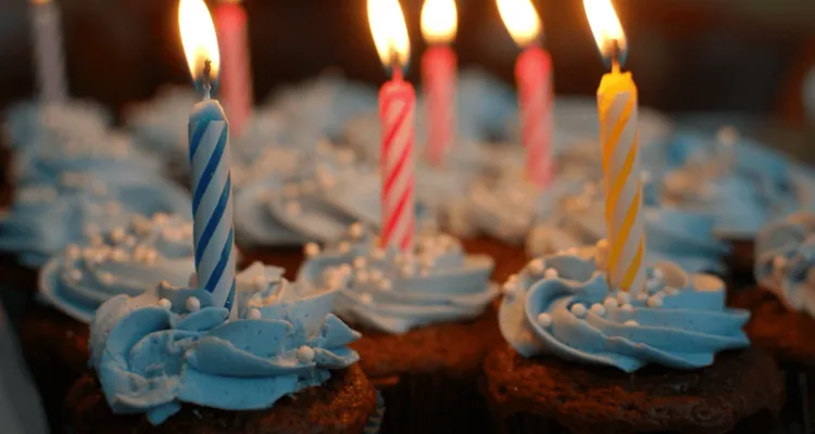 En handfull cupcakes med glasyr och födelsedagsljus i