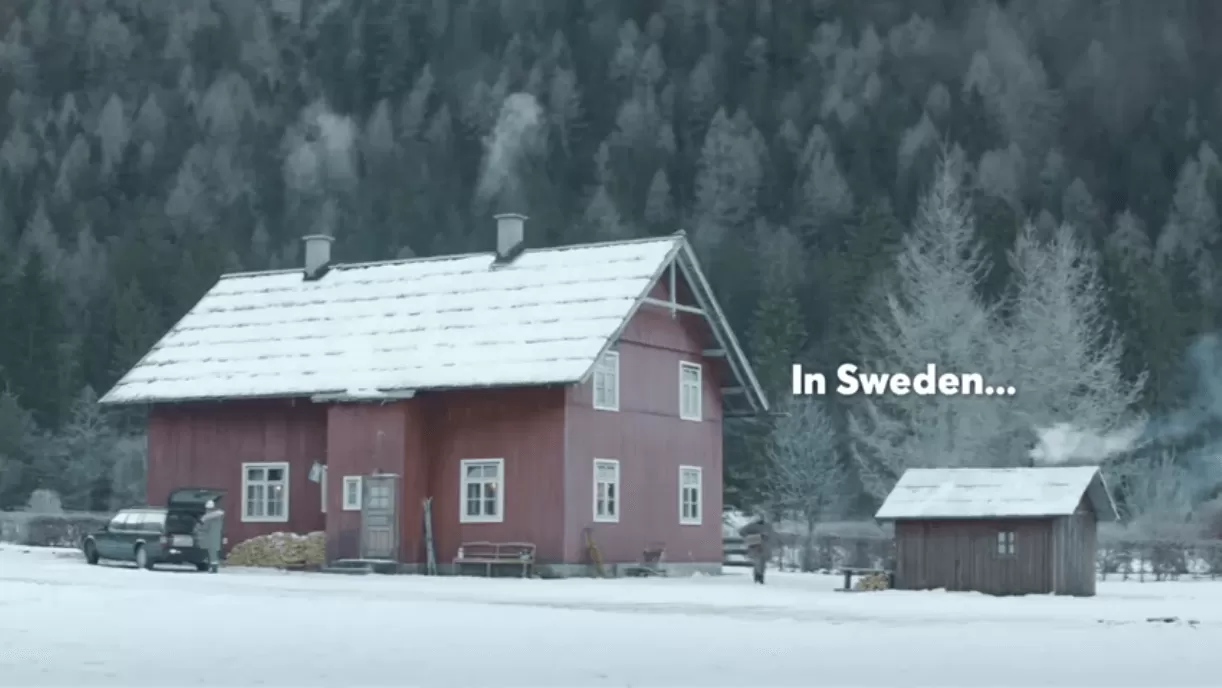 Rödmålad stuga i vinterlandskap med texten "In Sweden"