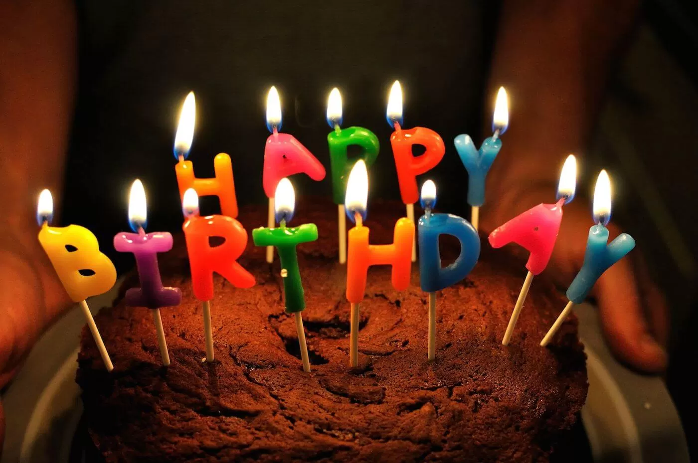 Tårta med ljus i form av bokstäver som bilder Happy Birthday